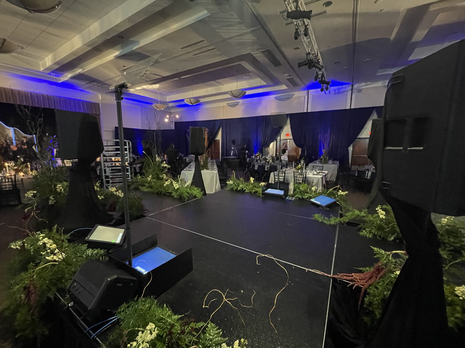 Gala ballroom stage with teleprompters and blue uplighting